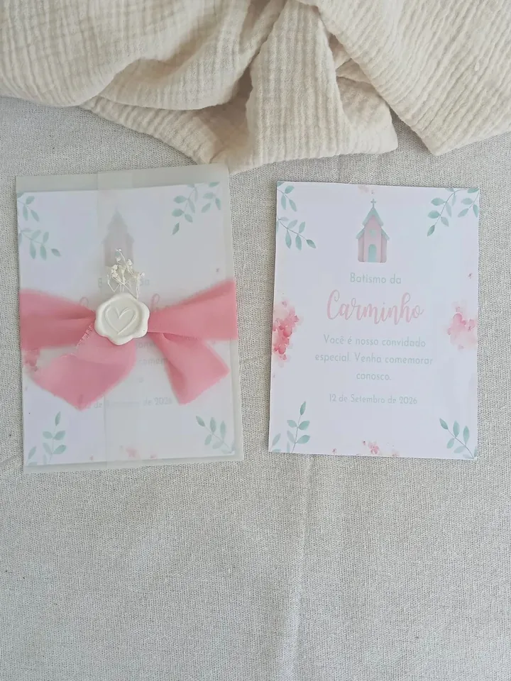 Convite de batismo com laço rosa e selo de lacre branco, ao lado do convite aberto